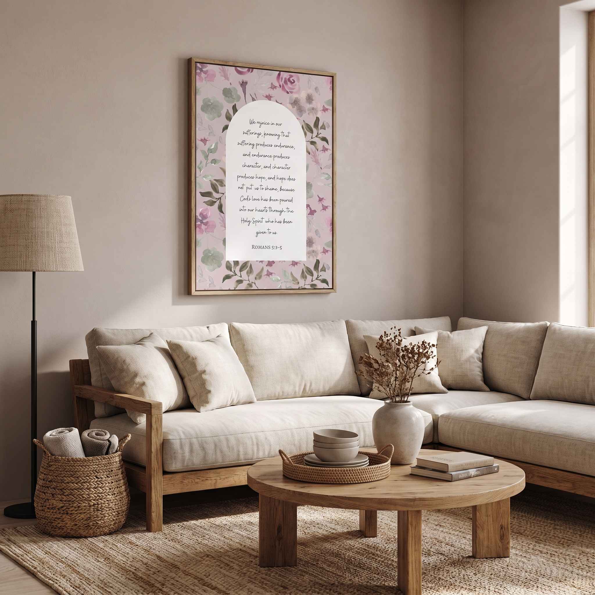 Framed Christian floral wall art titled Romans 5:3–5 featuring "Hope does not put us to shame" with watercolor botanical artwork, displayed on a light wall above a beige sectional sofa in a rustic modern living room.