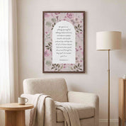 Framed vintage Christian floral wall art titled Romans 5:3–5 featuring "Hope does not put us to shame" with watercolor botanical artwork, displayed on a light wall above a beige armchair and floor lamp in a soft organic modern reading nook.