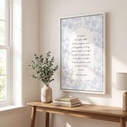 Framed Christian floral scripture wall art titled Romans 8:38–39 featuring "Nothing can separate us from the love of God" with blue botanical artwork, displayed in a white frame on a light wall above a wooden console table in a bright bedroom near a window.