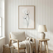 Minimalist Floral Wall Art featuring tulip line drawing in a light wood frame, styled above a neutral armchair and wooden side table with a ceramic lamp.