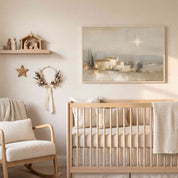 Framed vintage Christmas Christian wall art titled The Star Over Bethlehem, depicting the glowing star above Bethlehem, displayed above a light wood crib in a soft organic modern nursery.