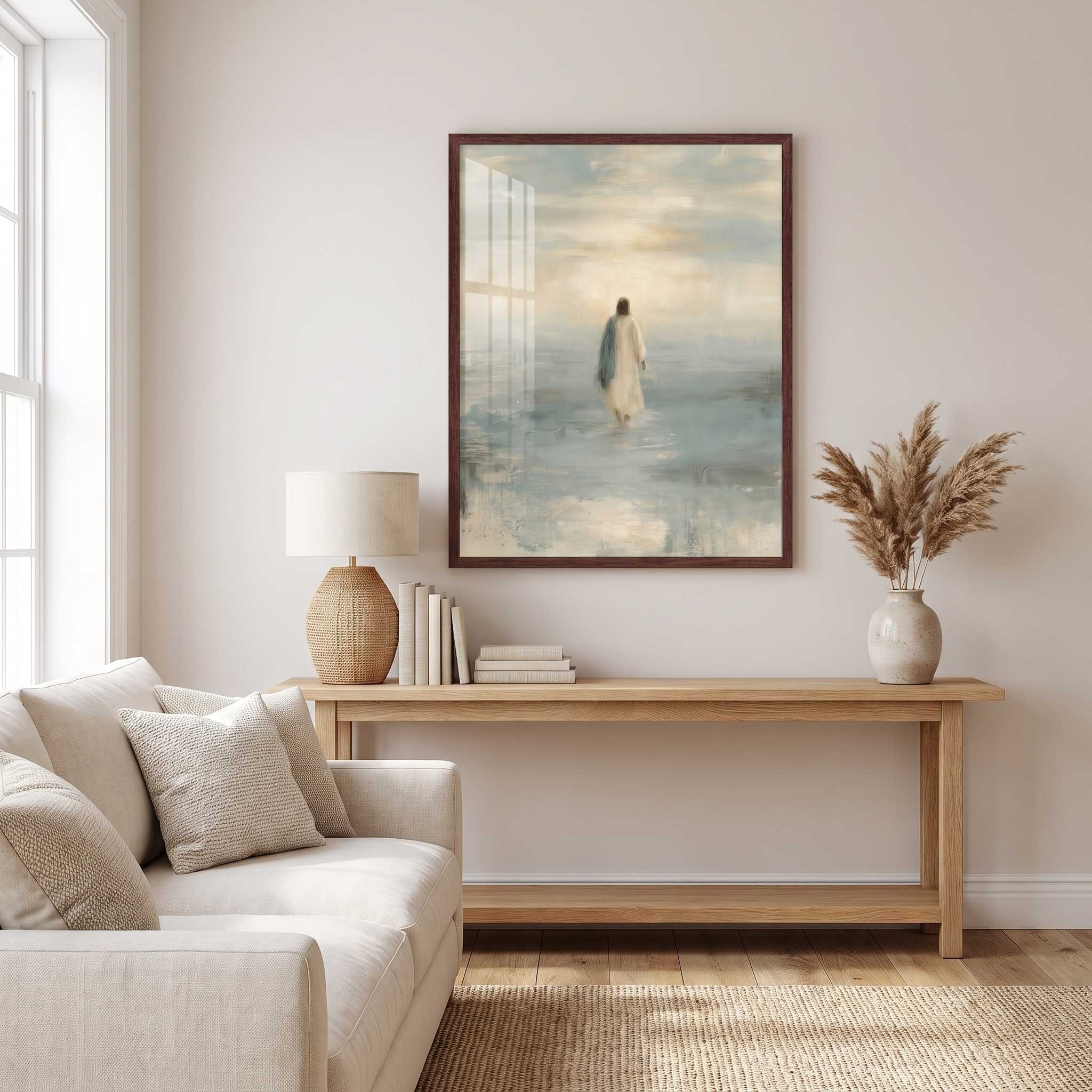 Framed Take Courage Jesus walking on water Christian wall art above a wooden console with books and a lamp beside a cream sofa in a sunlit living room.