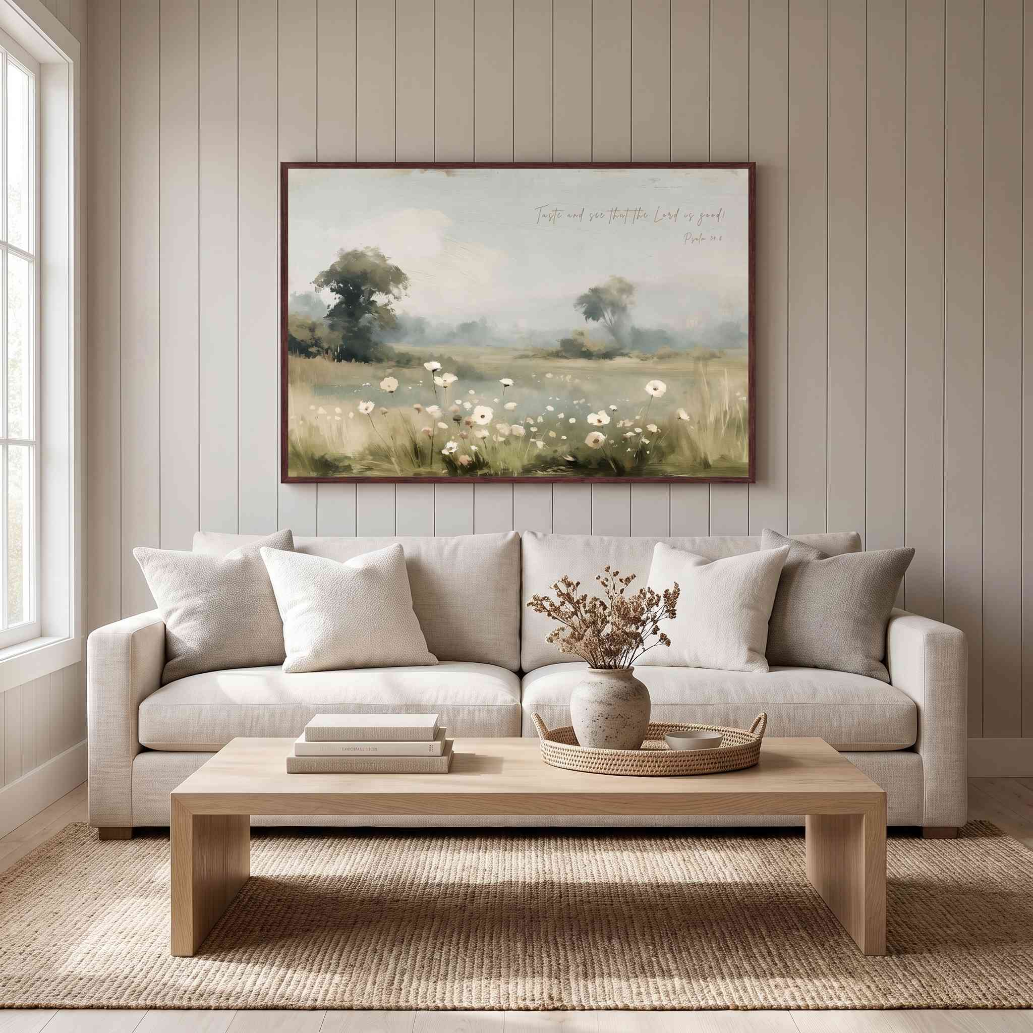 Framed vintage Psalm 34:8 wildflower landscape canvas wall art hanging above a beige sofa on a beadboard wall in a soft organic modern living room.