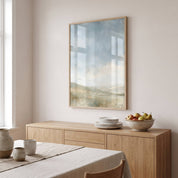 The Earth Is the Lord’s Christian landscape framed print with window reflections above a wooden sideboard with plates and fruit in a bright dining room.