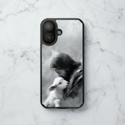 The Good Shepherd MagSafe® clear iPhone case featuring black and white watercolor artwork of Jesus holding a lamb displayed on a white marble surface in a minimalist Christian aesthetic setting