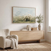 Framed vintage Psalm 103:8 wildflower landscape canvas wall art hanging above a light wood credenza next to a boucle armchair in a bright organic modern living room.