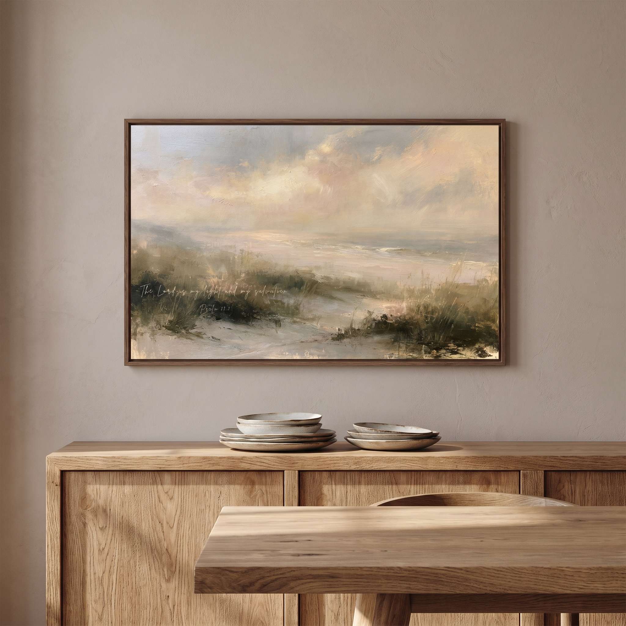 Framed vintage Psalm 27:1 Christian landscape canvas wall art featuring coastal dunes hanging above a wooden sideboard with stacked ceramics in a soft organic modern dining room.