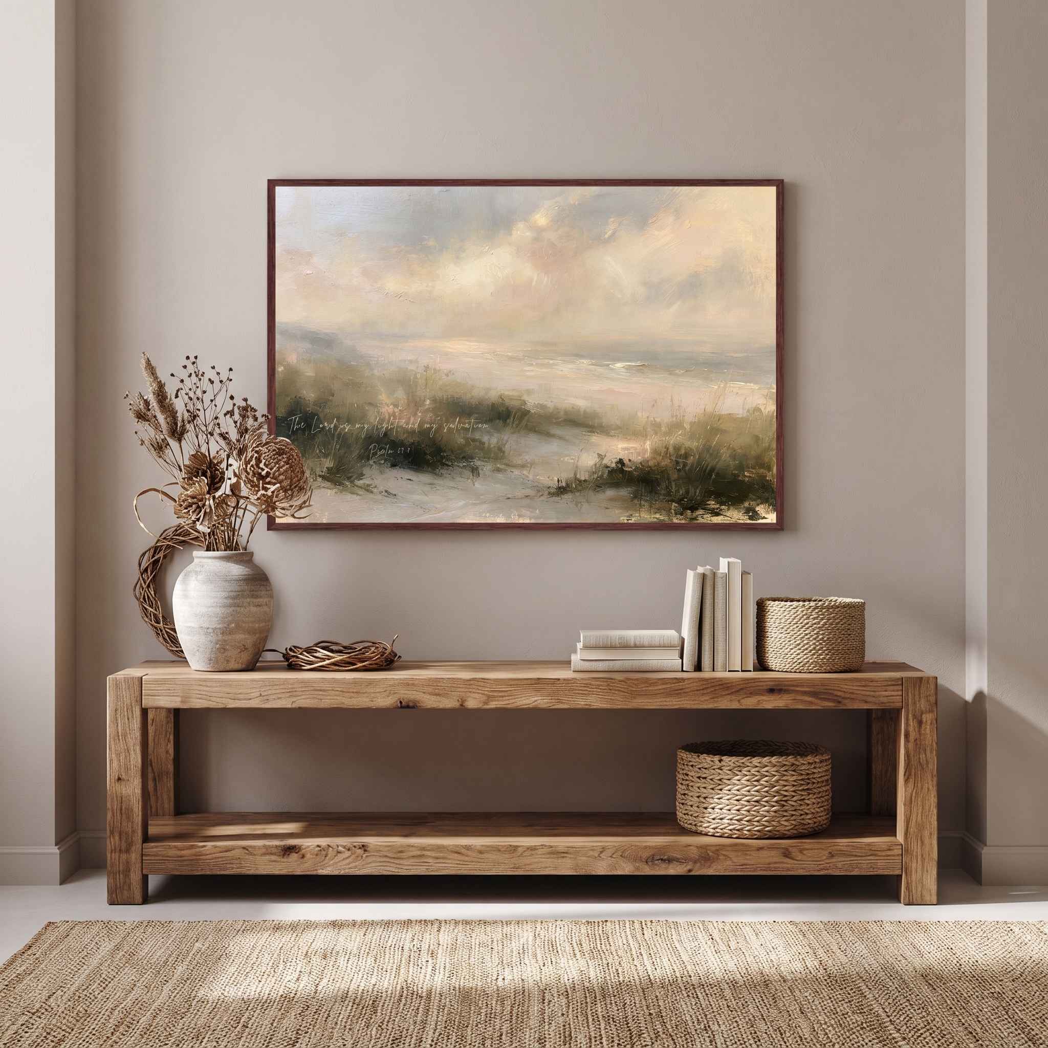 Framed vintage Psalm 27:1 Christian landscape canvas wall art featuring coastal dunes hanging above a rustic wooden console table with a ceramic vase, stacked books, and woven baskets in a warm entryway.