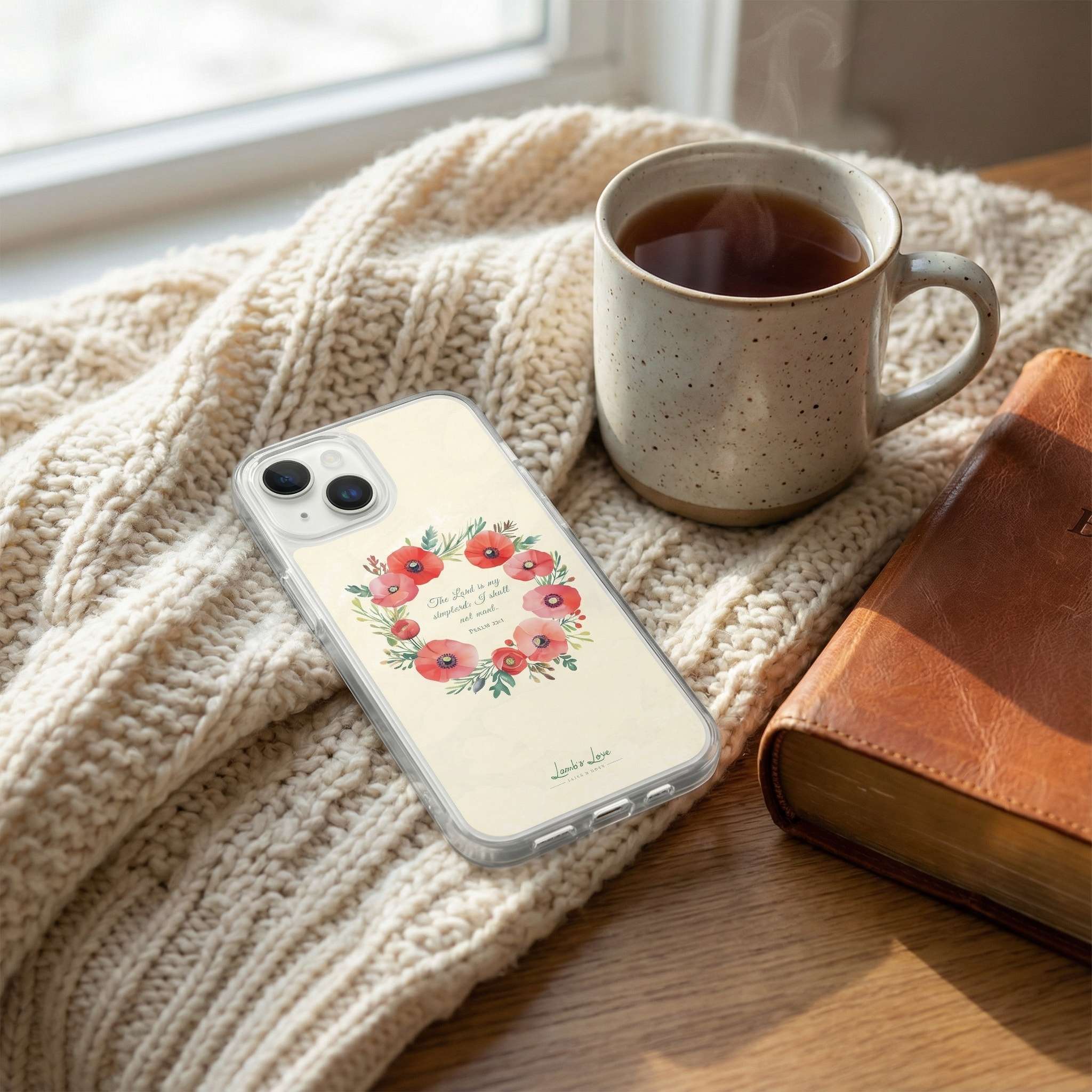 Phone case with floral design on a textured surface with a mug and book