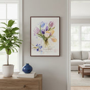 Framed floral artwork on a wall in a living room with a plant and books on a wooden surface.