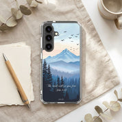 Christian Samsung Phone case with mountain and forest design on a desk with a pen and mug.