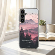Phone case with mountain and tree design on a desk with a book and mug