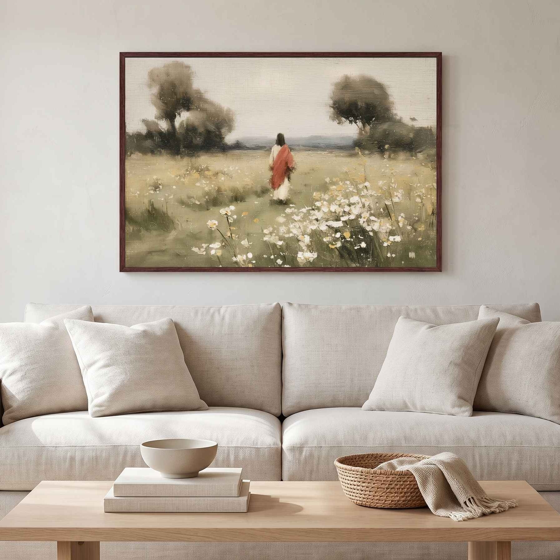 Framed Christian wall art titled Walking with Jesus, displaying Christ walking through a meadow of wildflowers above a light gray sofa.