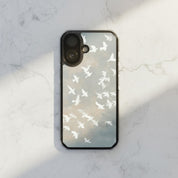 Wings of Peace MagSafe® Christian phone case featuring soft watercolor birds flying across a neutral sky displayed on a white marble surface in a minimalist modern aesthetic setting