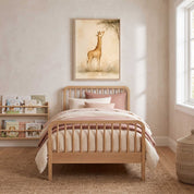 Framed Wonderfully Made giraffe Christian kids wall art above a wooden bed with pink and cream bedding, beside bookshelves in a sunlit child’s room.